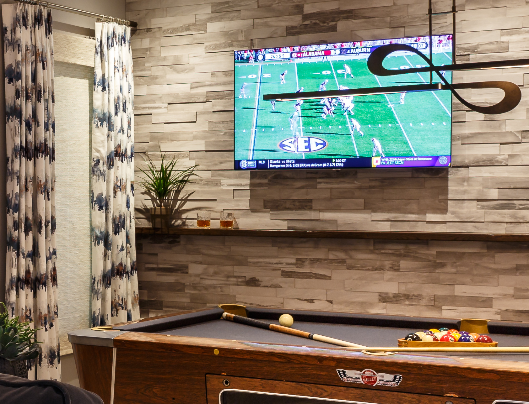 Stone wall behind pool floating shelf light fixture over pool table